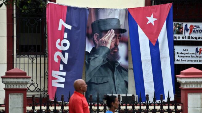 Dos cubanos pasan ante un gran cartel de Fidel en una conmemoración del Asalto al Cuartel Moncada.