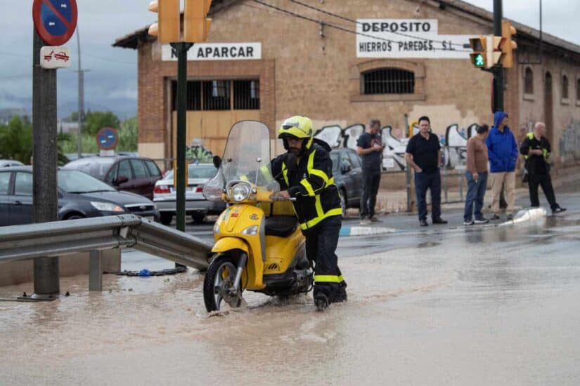 Un cartero empuja su moto en Molina de Segura, (Murcia), inundada por las intensas lluvias.