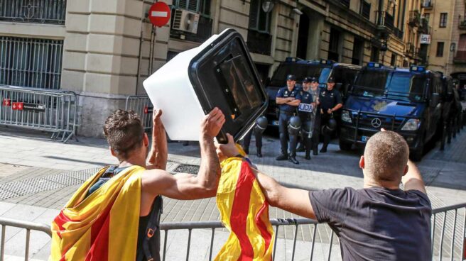 Dos jóvenes independentistas muestran esta semana una urna empleada el 1-O a los policías nacionales apostados ante la Jefatura Superior de Barcelona.