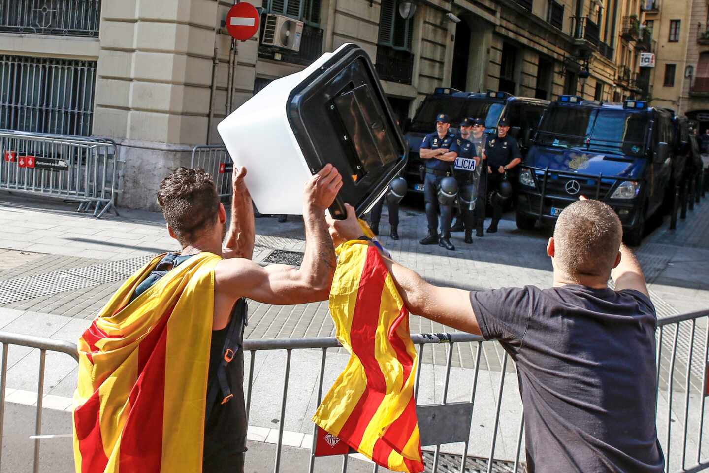 Dos jóvenes independentistas muestran esta semana una urna empleada el 1-O a los policías nacionales apostados ante la Jefatura Superior de Barcelona.