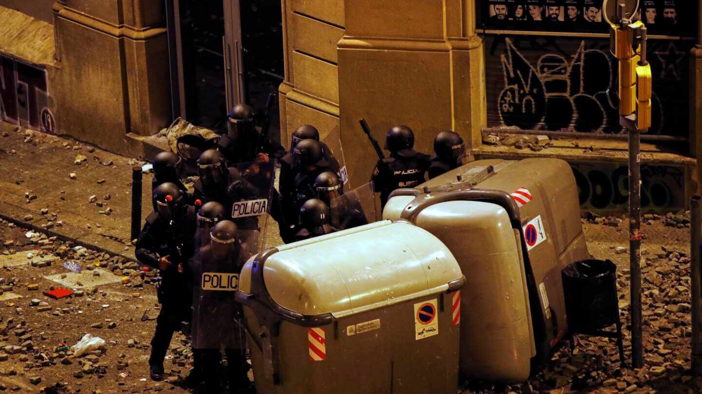 Un grupo de antidisturbios, parapetados tras unos contenedores junto a la Plaza de Urquinaona (Barcelona) en medio de un manto de piedras durante los altercados de octubre.