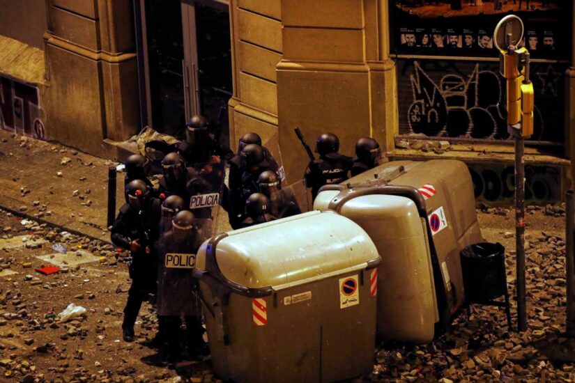 Un grupo de antidisturbios, parapetados tras unos contenedores junto a la Plaza de Urquinaona (Barcelona) en medio de un manto de piedras durante los altercados de octubre.