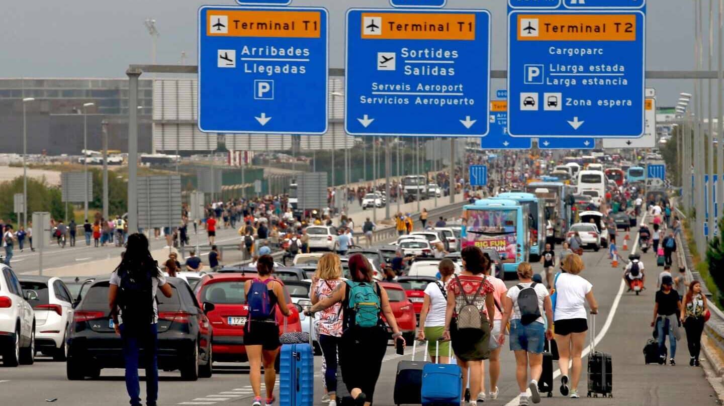 Pasajeros acceden a pie al aeropuerto de El Prat por el corte de los accesos por manifestantes independentistas.