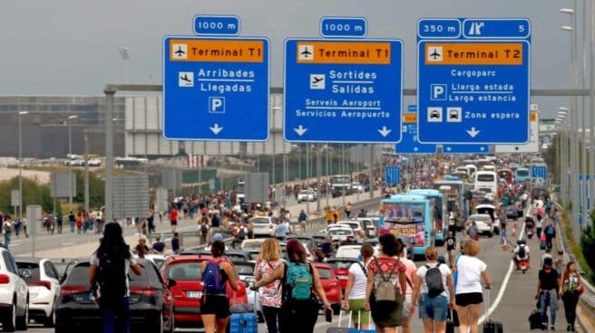 Pasajeros acceden a pie al aeropuerto de El Prat por el corte de los accesos por manifestantes independentistas.