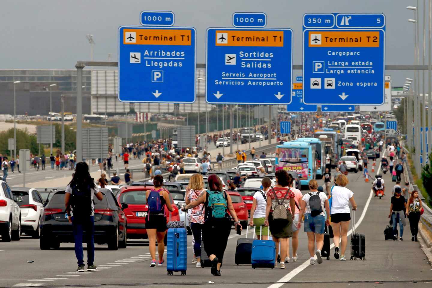 Pasajeros acceden a pie al aeropuerto de El Prat por el corte de los accesos por manifestantes independentistas.