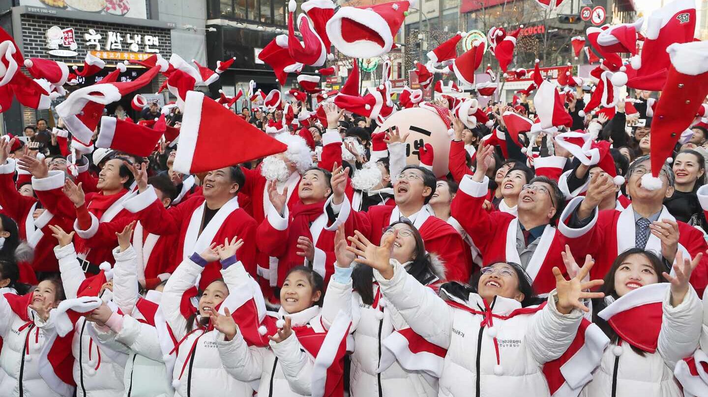 Decenas de niños y adultos lanzan al aire sus gorros de Santa Claus para celebrar la Navidad y el inicio de programas de voluntariado para los más necesitados en Corea del Sur.