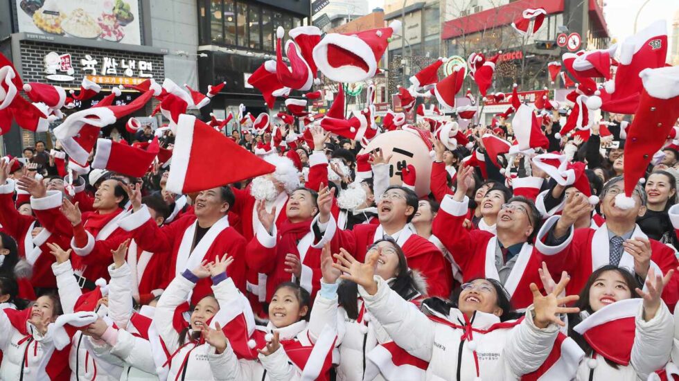 Decenas de niños y adultos lanzan al aire sus gorros de Santa Claus para celebrar la Navidad y el inicio de programas de voluntariado para los más necesitados en Corea del Sur.