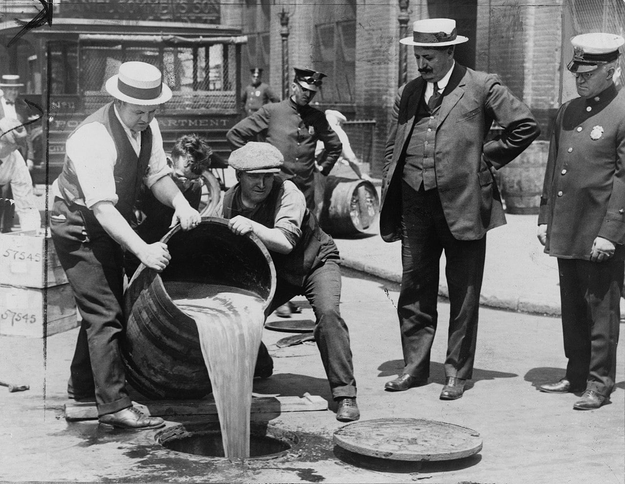 Hombres de las autoridades estadounidenses vierten licor en una alcantarilla durante la Ley Seca.