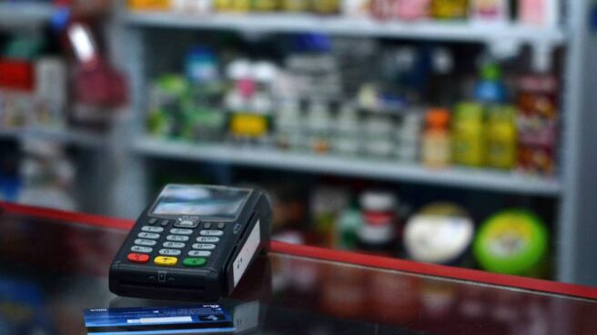 El comercio español soporta cerca de 550 millones de euros por comisiones de pagos con tarjetas Tarjeta de crédito junto a un terminal de pago.