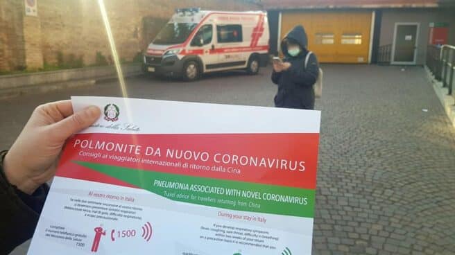 Una persona sostiene un folleto informativo emitido por el Ministerio de Salud italiano sobre los síntomas del coronavirus