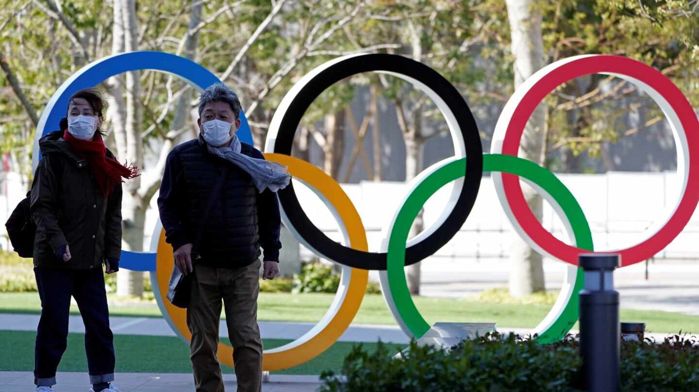 Dos personas con mascarilla caminan en la entrad del Comité Olímpico de Japón