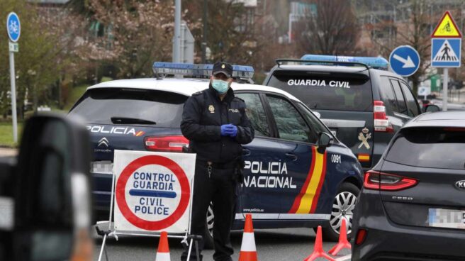 Un policía nacional se protege con una mascarilla en uno de los controles de frontera establecidos tras declararse el estado de alarma.