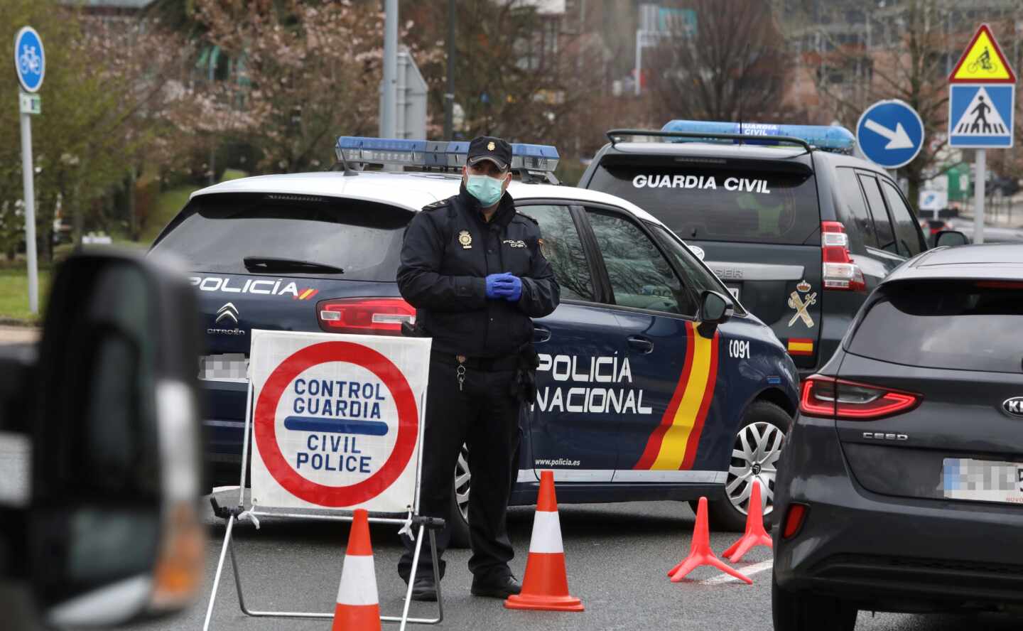 Un policía nacional se protege con una mascarilla en uno de los controles de frontera establecidos tras declararse el estado de alarma.