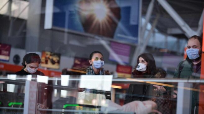 Pasajeros con mascarillas en un aeropuerto.