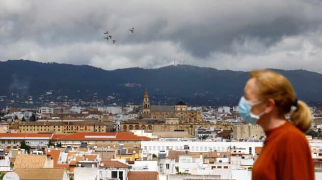 Una mujer camina con el fondo de la Mezquita-Catedral de Córdoba y un cielo cubierto de nubes oscuras.