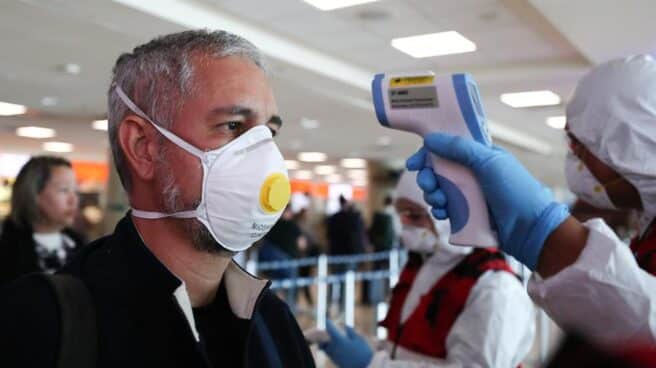 Un hombre con mascarilla pasa un control en el aeropuerto de Quito