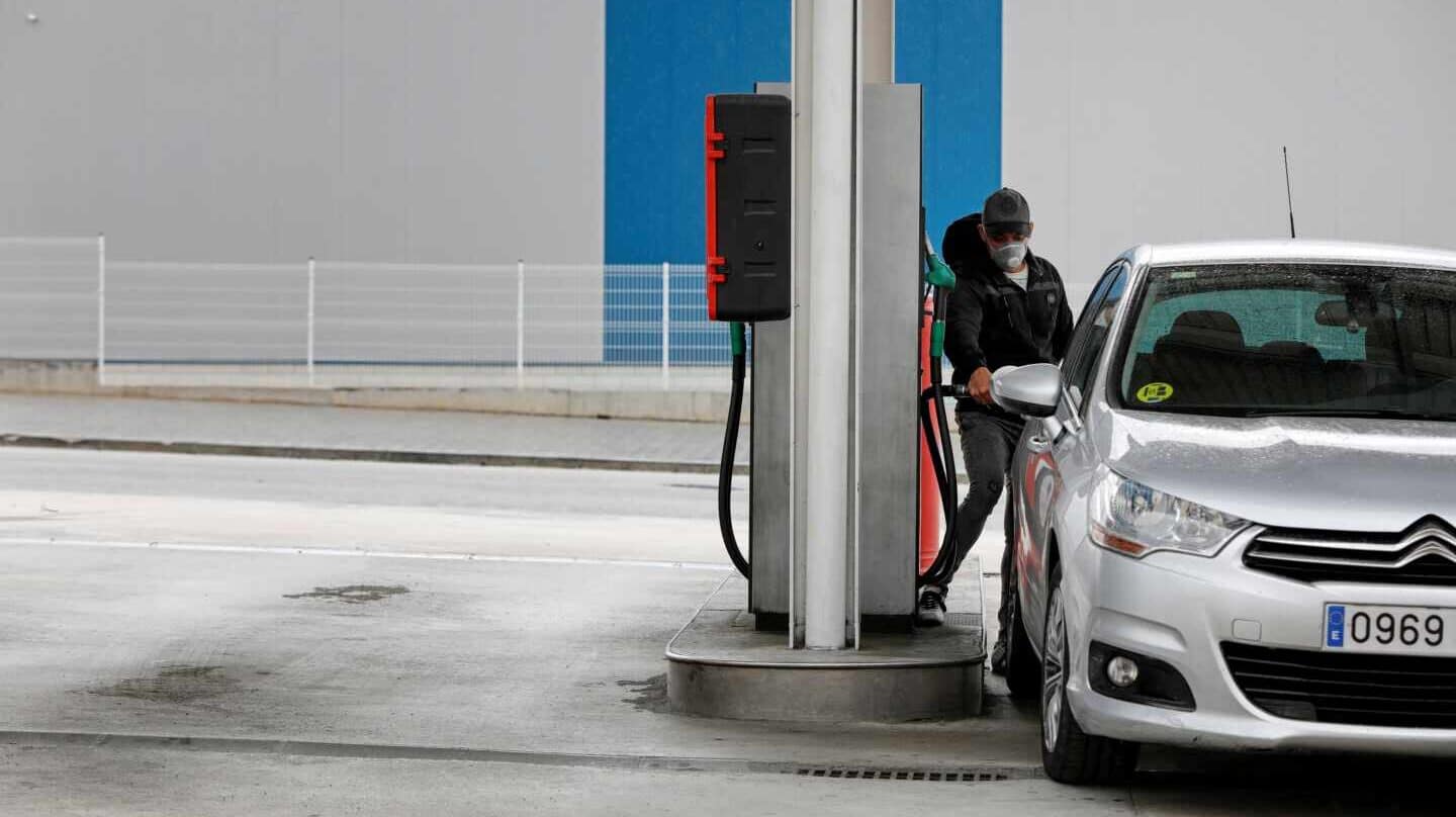 Un conductor con mascarilla reposta en una gasolinera.