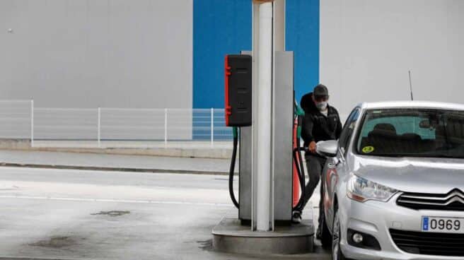 Un conductor con mascarilla reposta en una gasolinera.