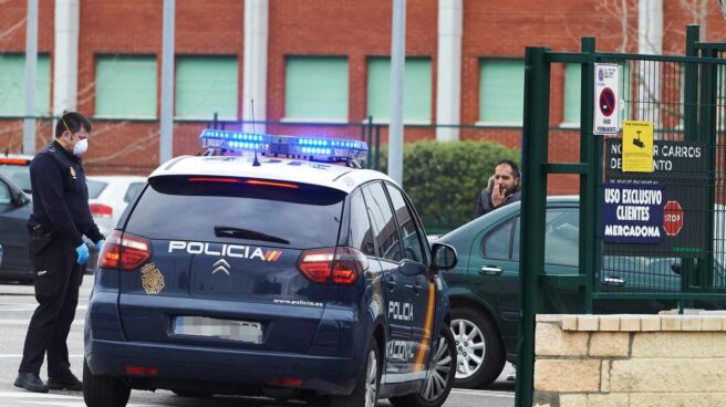 Un policía nacional, protegido con una mascarilla, junto al aparcamiento de un supermercado en Santander.