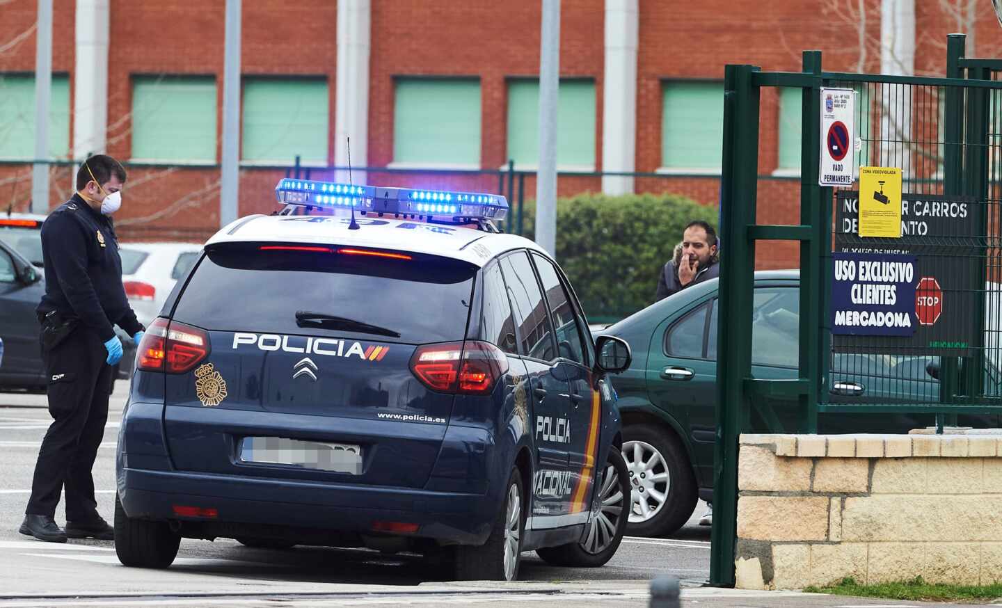 Un policía nacional, protegido con una mascarilla, junto al aparcamiento de un supermercado en Santander.