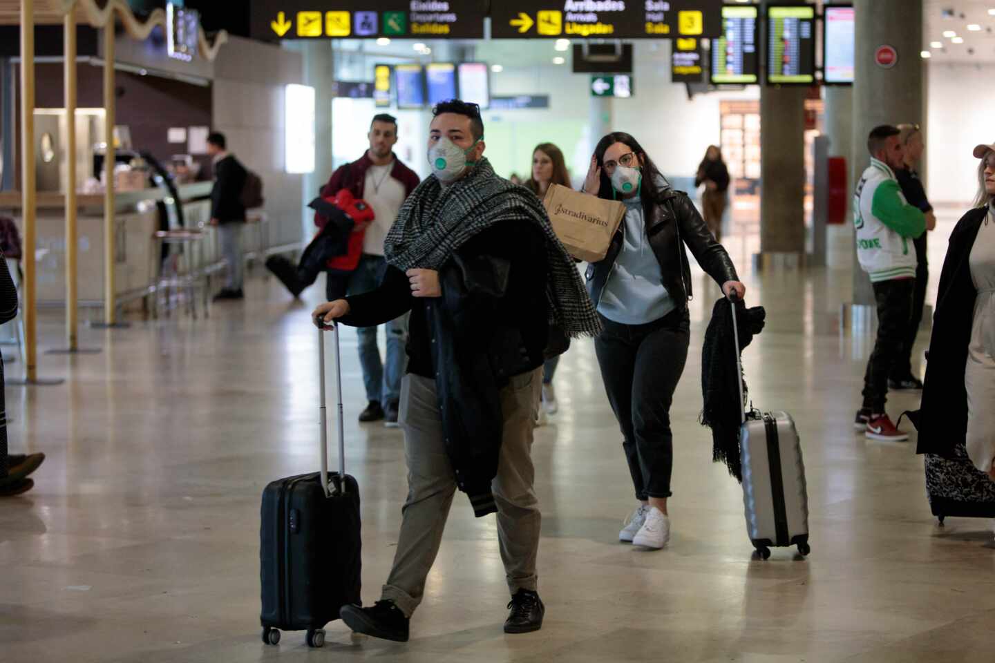 Pasajeros con mascarillas por el coronavirus en un aeropuerto.