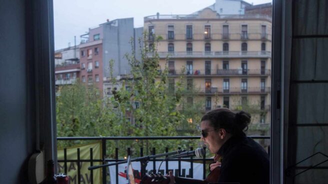 Un joven canta para sus vecinos desde el balcón de su casa, en Barcelona.