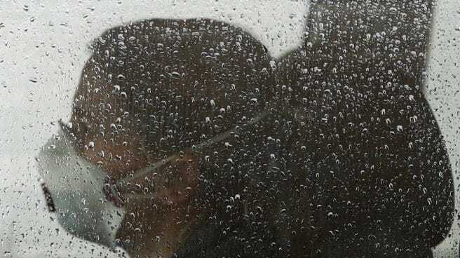 Una persona en el interior de su vehículo con una mascarilla puesta en una jornada de lluvia.