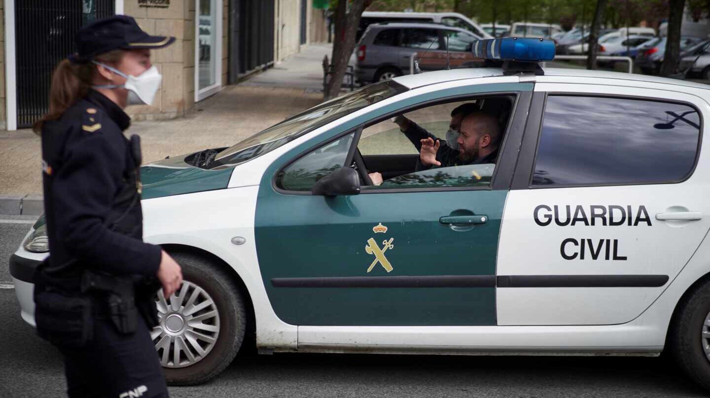 Un patrullero de la Guardia Civil pasa junto a una funcionaria del Cuerpo Nacional durante el estado de alarma.