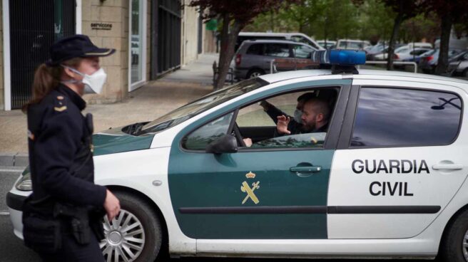 Guardias civiles y policías esperan desde hace 5 años un seguro de responsabilidad civil que les cubra Un patrullero de la Guardia Civil pasa junto a una funcionaria del Cuerpo Nacional durante el estado de alarma.