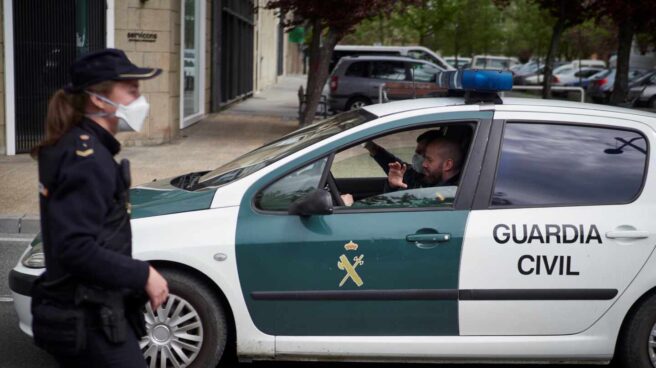 Un patrullero de la Guardia Civil pasa junto a una funcionaria del Cuerpo Nacional durante el estado de alarma.