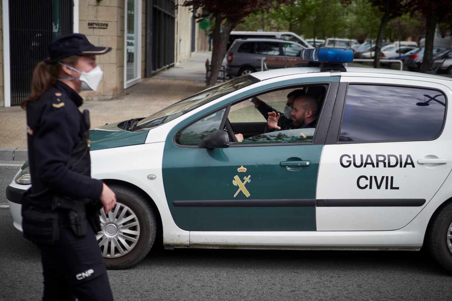 Un patrullero de la Guardia Civil pasa junto a una funcionaria del Cuerpo Nacional durante el estado de alarma.