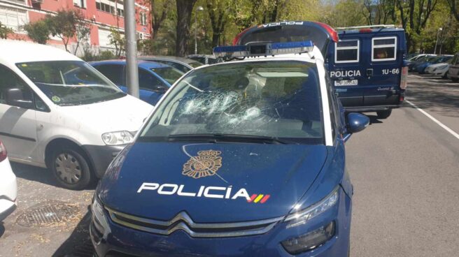 Uno de los coches de la Policía Nacional con la luna rota tras ser golpeada por el detenido.