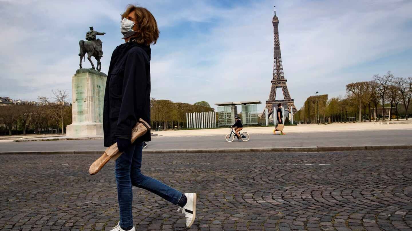 Una mujer pasa por delante de la Torre Eiffel durante el confinamiento en París