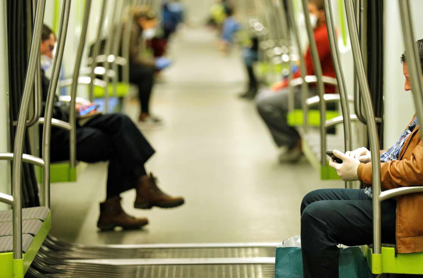 Dos hombres consultan sus teléfonos móviles en el transporte público.