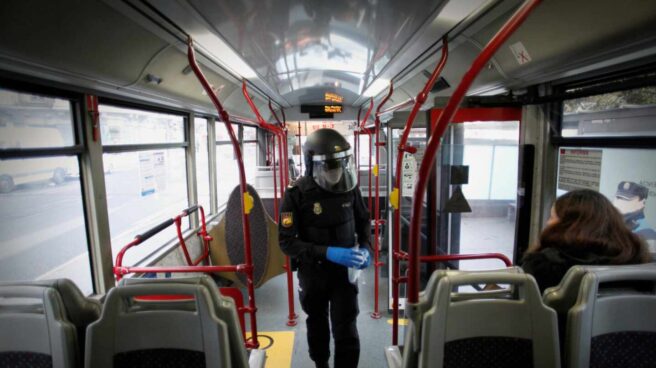 Un policía reparte mascarillas a los pasajeros de un autobús en A Coruña.