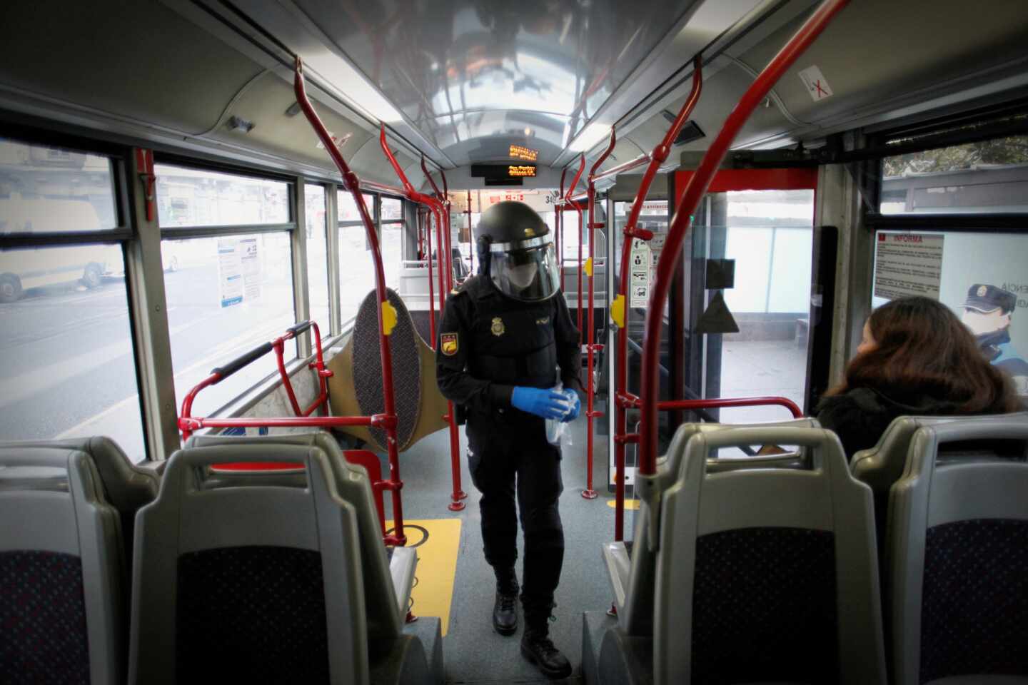 Un policía reparte mascarillas a los pasajeros de un autobús en A Coruña.