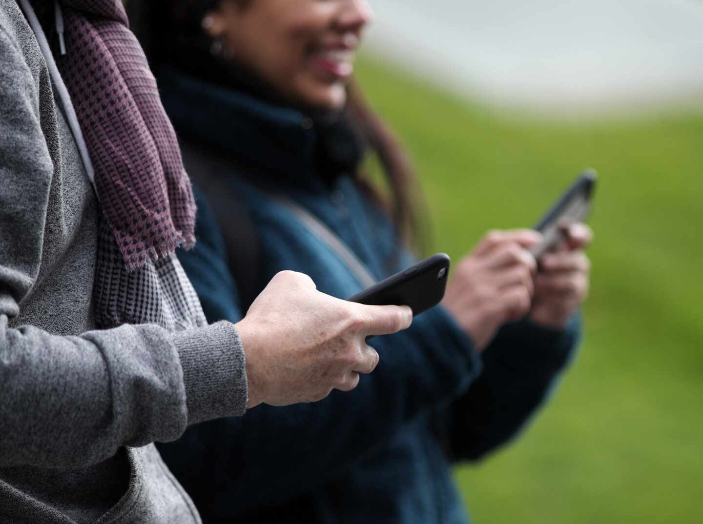 Dos paseantes utilizando su teléfono móvil.