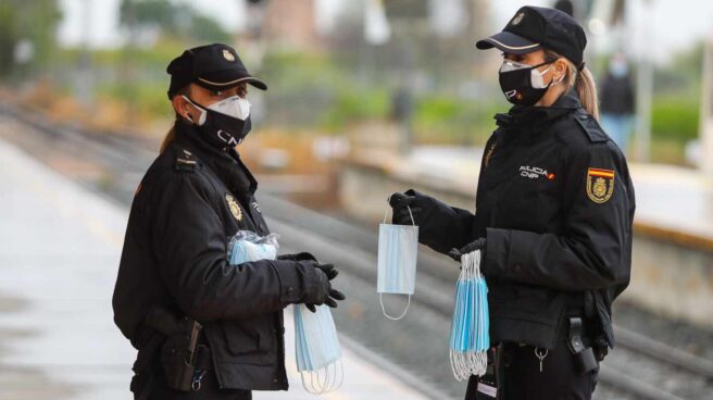 El SUP pide investigar si se evitó reforzar la protección de los policías por "cuestiones estéticas" Policías nacionales, repartiendo mascarillas en una estación de tren.