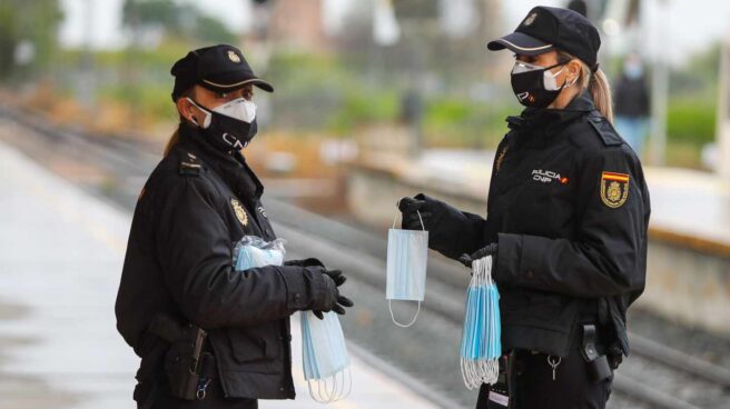 Policías nacionales, repartiendo mascarillas en una estación de tren.