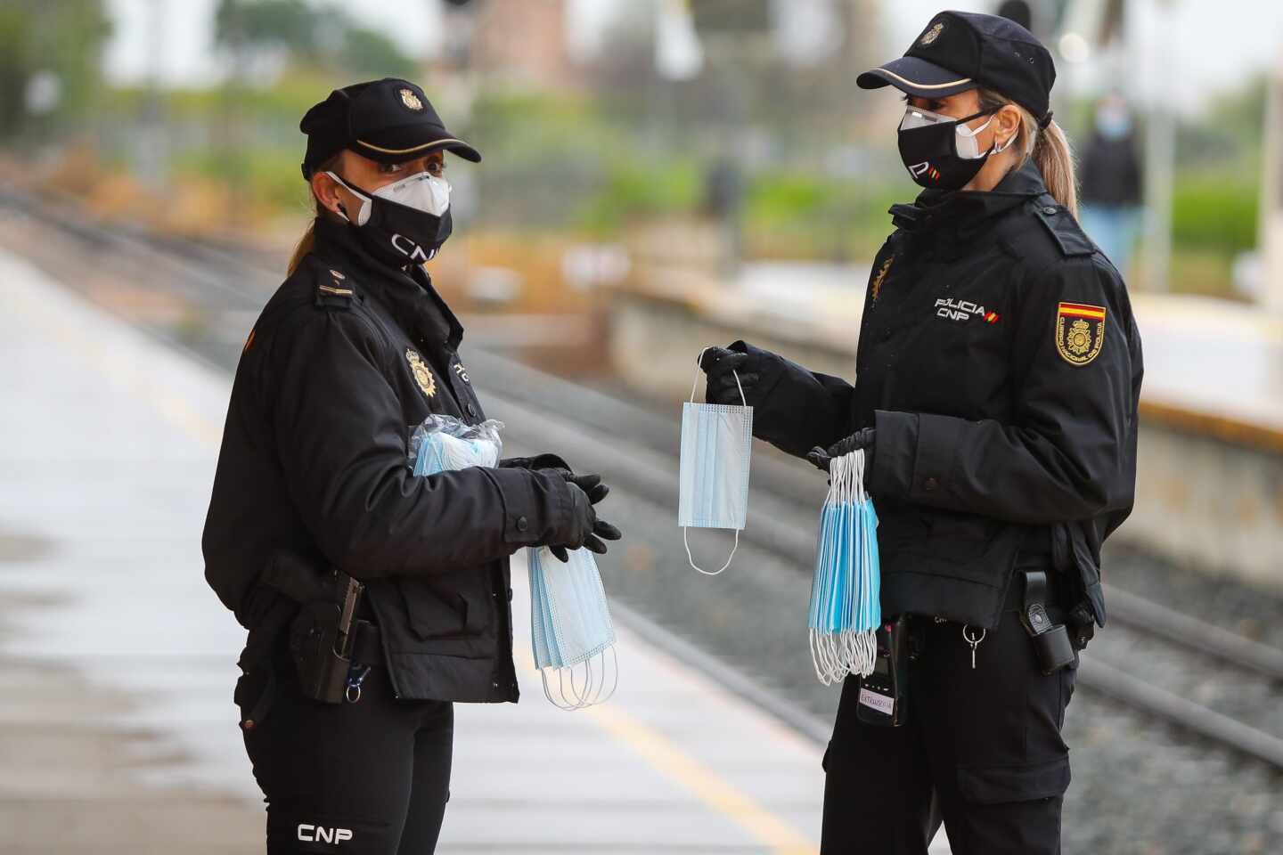 Policías nacionales, repartiendo mascarillas en una estación de tren.