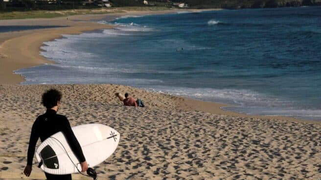 Un hombre con una tabla de surf este lunes en los arenales próximos a Ferrol (Galicia).