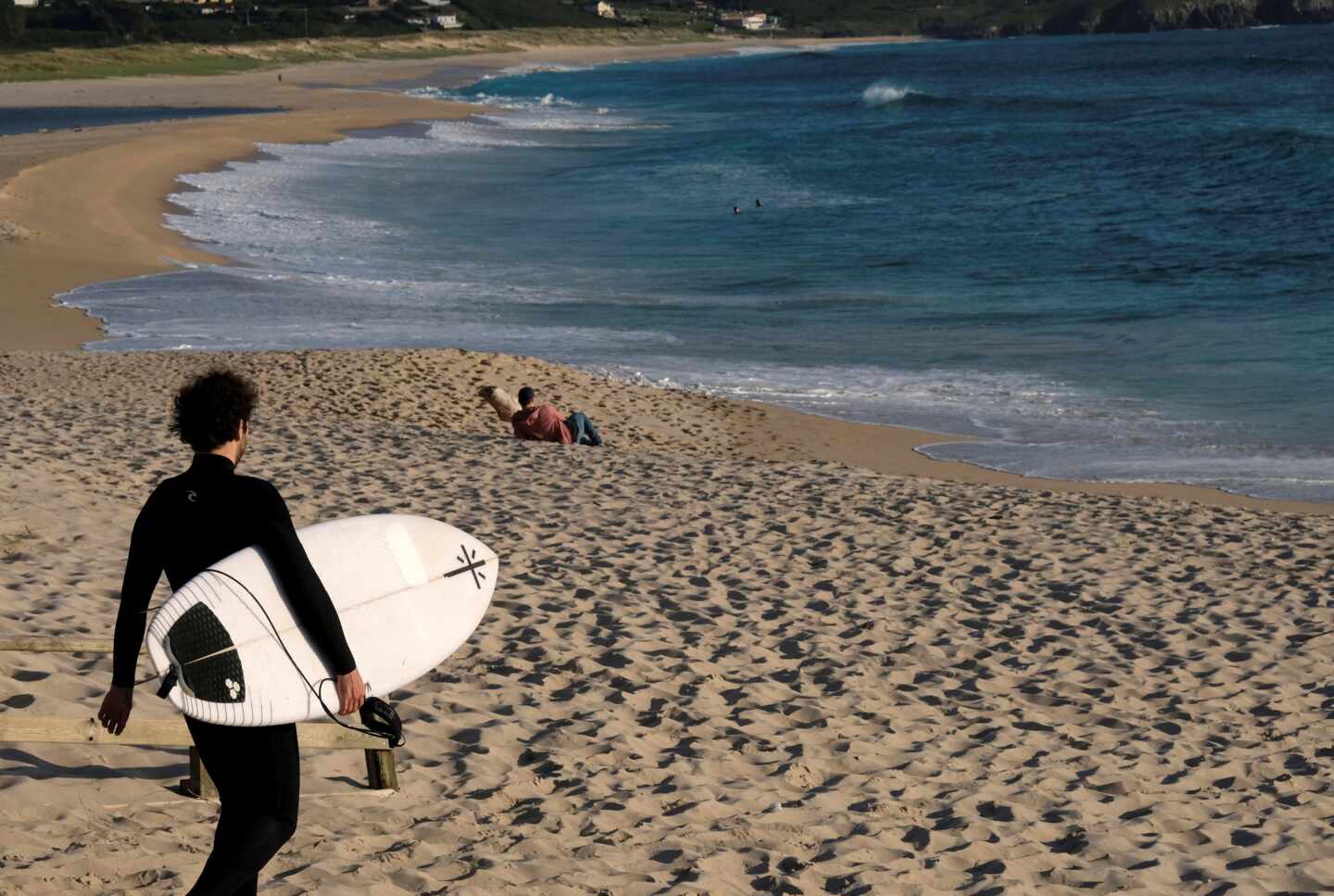 Un hombre con una tabla de surf este lunes en los arenales próximos a Ferrol (Galicia).