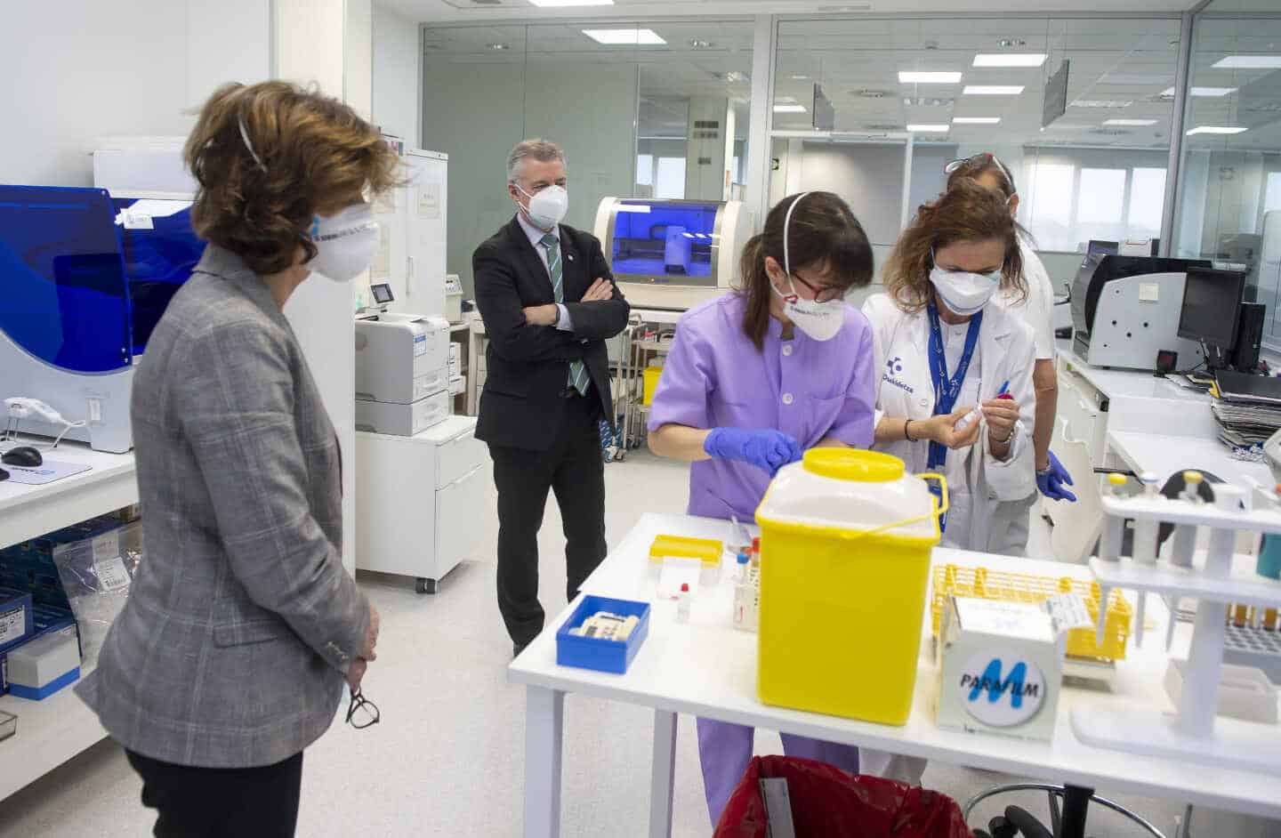 La consejera Nekane Murga, junto al lehendakari Iñigo Urkullu, observan a técnicos de laboratorio de un hospital.