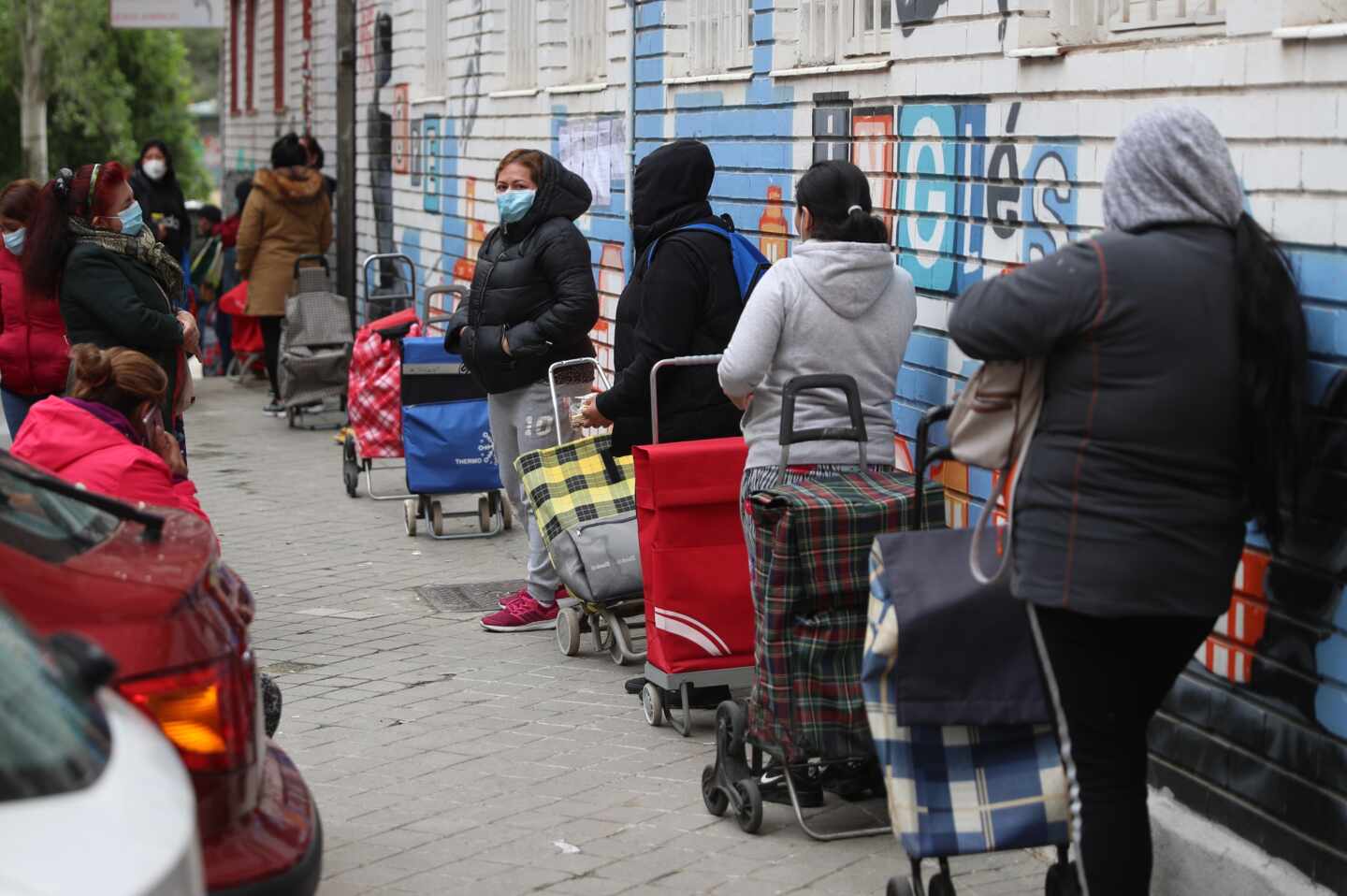 Colas para recoger comida repartida por la Asociación de Vecinos de Aluche, en Madrid.