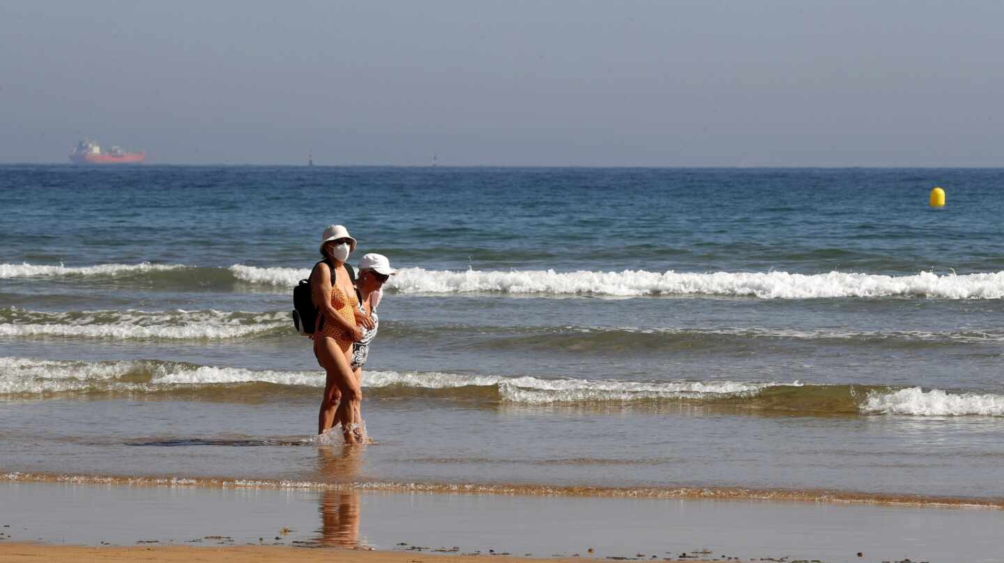 Dos bañistas con mascarilla en la playa de Gijón.