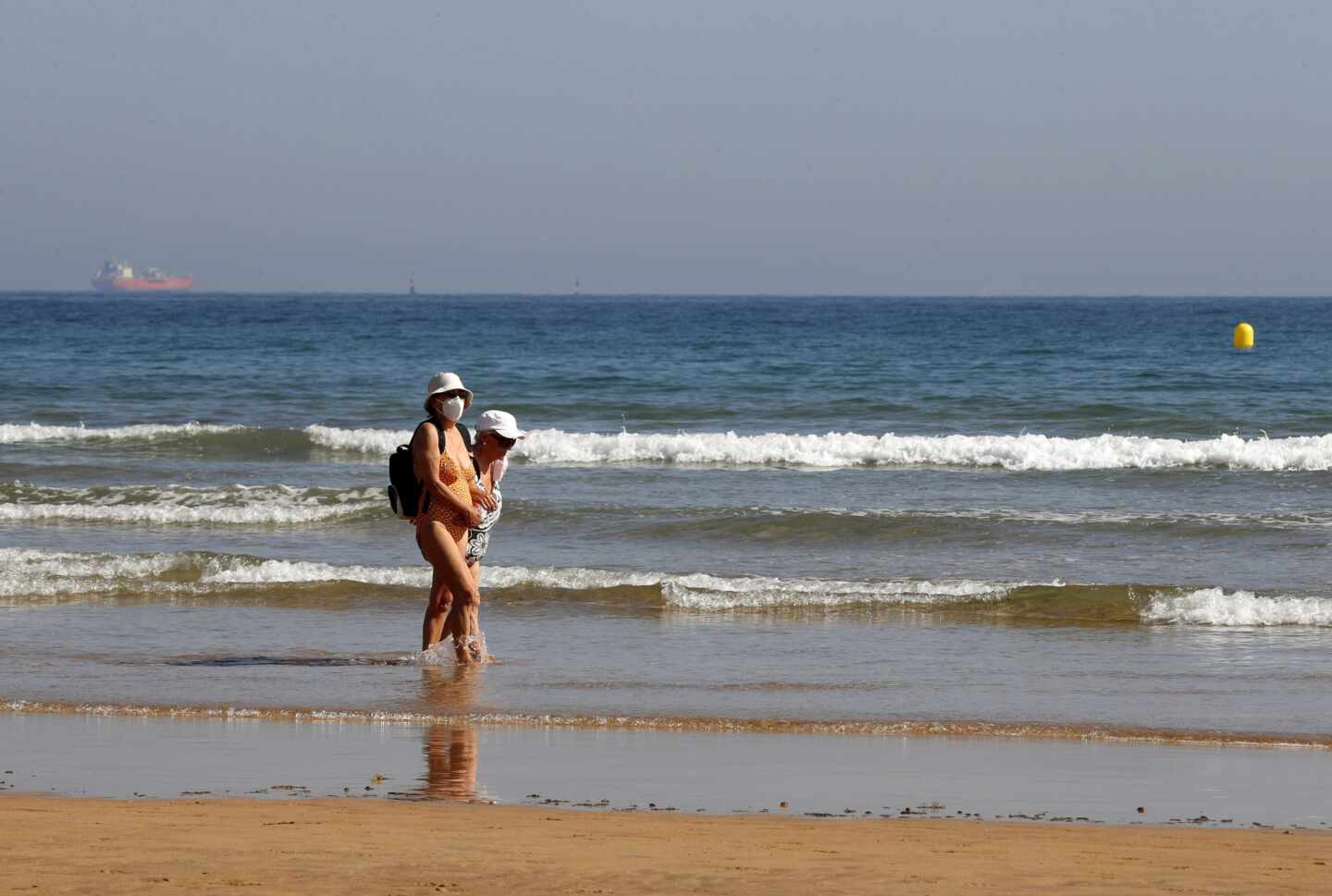 Dos bañistas con mascarilla en la playa de Gijón.