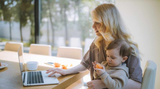 woman-carrying-her-baby-and-working-on-a-laptop-4079281