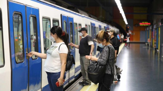 Viajeros con mascarillas entrando a un tren de Metro de Madrid.