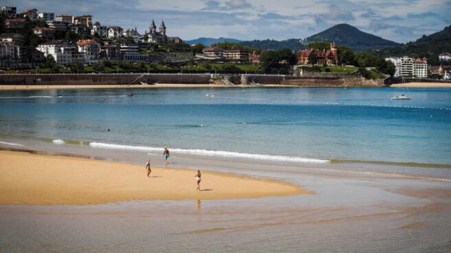 Varias personas pasean por la playa de La Concha de San Sebastián.