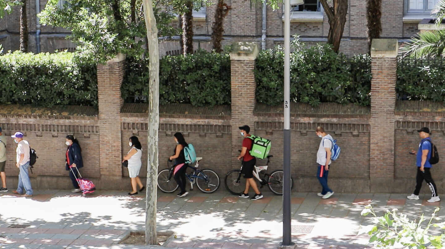 Dos riders hacen cola en Martínez Campos para conseguir una bolsa de comida